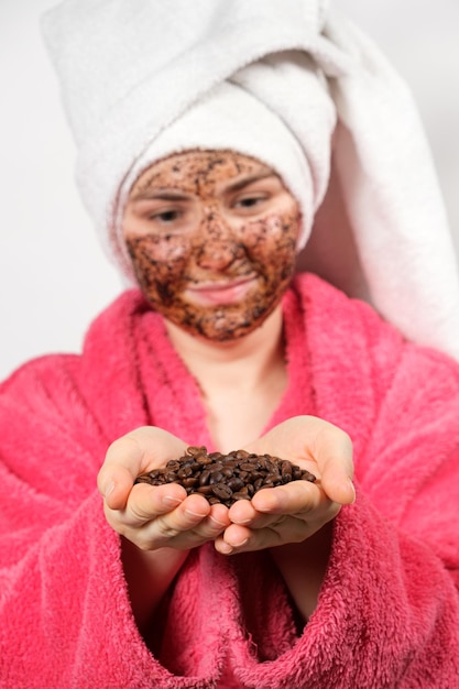 Een vrouw met een koffiemasker op haar gezicht houdt koffiebonen vast