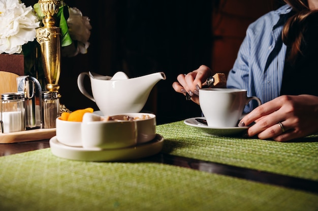 Een vrouw met een kop hete thee in haar handen zit in het restaurant Het meisje drinkt aromatische thee Geniet van het moment neem een pauze