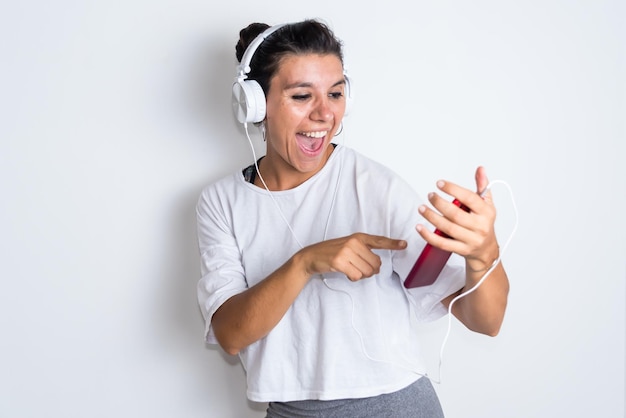 Een vrouw met een koptelefoon wijst naar een telefoon met een rode telefoon in haar hand.