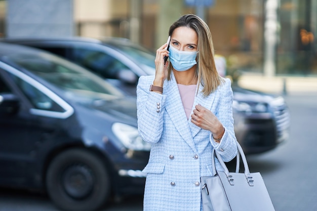 Een vrouw met een masker die op een mobiele telefoon praat. Hoge kwaliteit foto