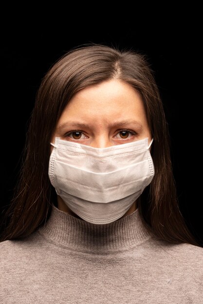 Een vrouw met een masker, een gespannen, rusteloze blik. bezorgdheid over een coronavirusinfectie, een poging tot bescherming. studio portret close-up. verticale foto