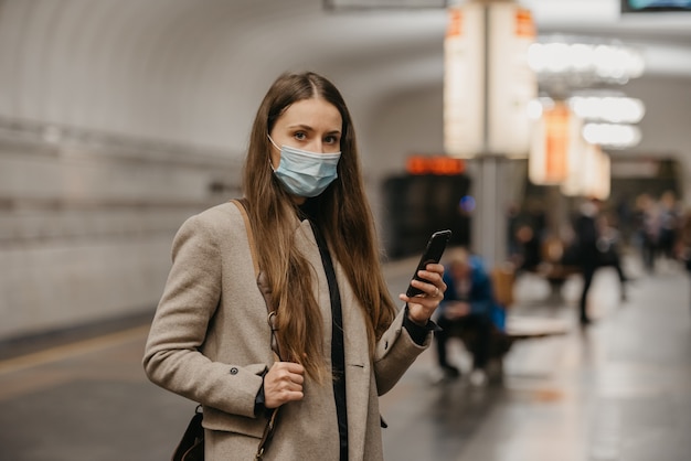 Een vrouw met een medisch gezichtsmasker bij het metrostation