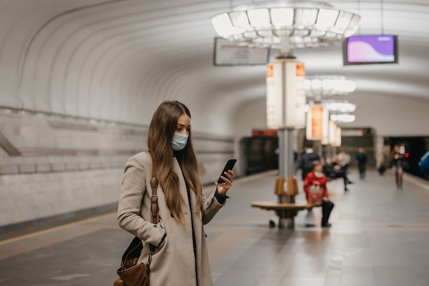 Een vrouw met een medisch gezichtsmasker bij het metrostation