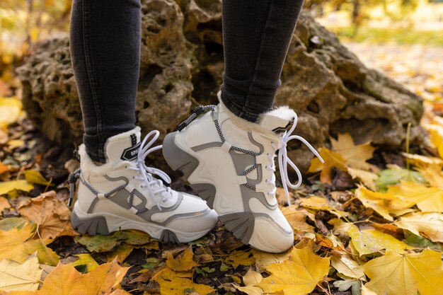 Foto een vrouw met een paar witte sneakers aan staat in de bladeren van een boom.