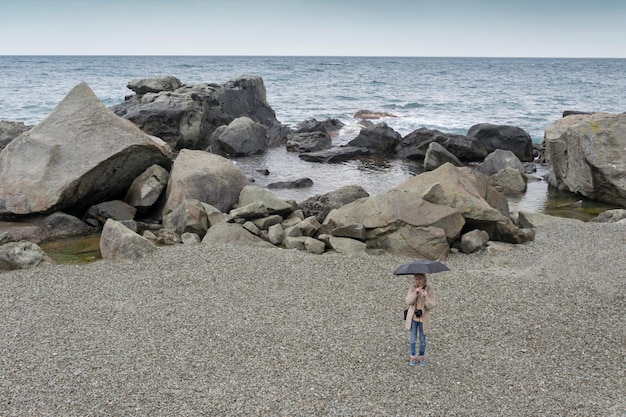 Een vrouw met een paraplu alleen op een leeg strand aan zee