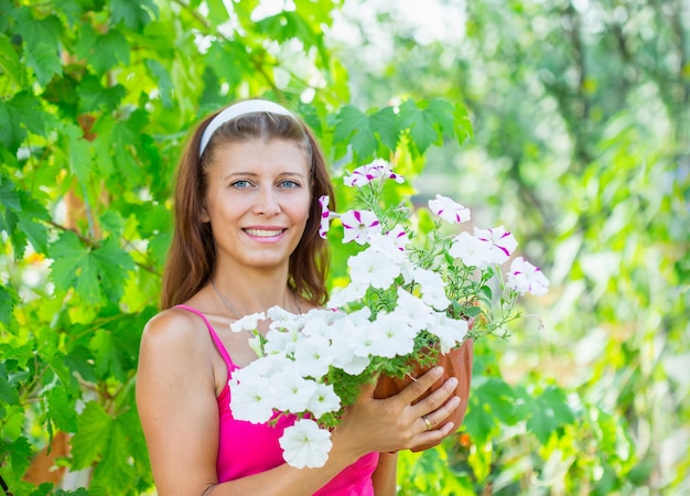 Een vrouw met een pot bloemen in de tuin