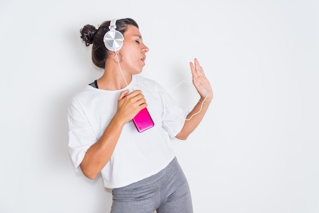 Een vrouw met een roze telefoon en koptelefoon die naar muziek luistert