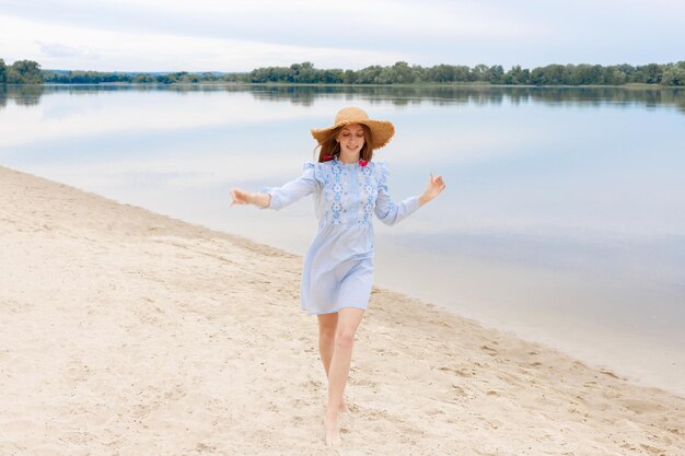 Een vrouw met een strohoed rent op het strand in de zomerse zomerstemming