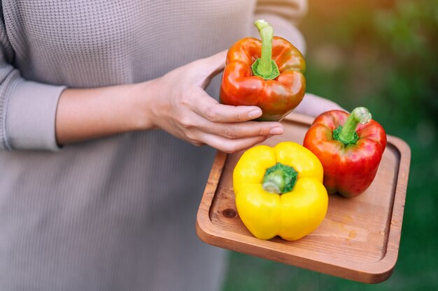 Een vrouw met een verse paprika in een houten dienblad