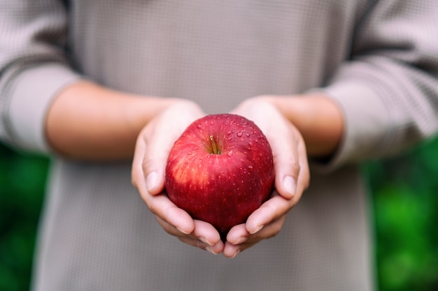 Een vrouw met een verse rode appel in de hand