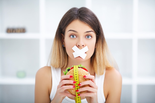 Foto een vrouw met een verzegelde mond probeert een hamburger te eten