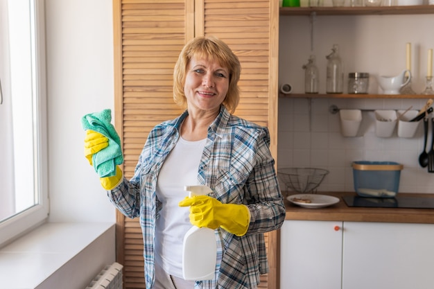 Een vrouw met een vod poetst en wast in de keuken