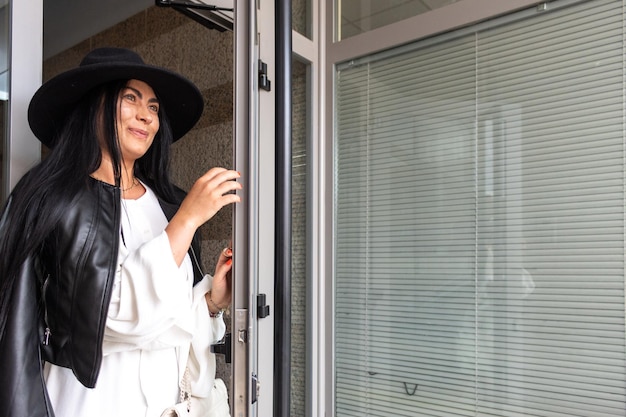 Een vrouw met een zwarte hoed die uit haar appartement komt