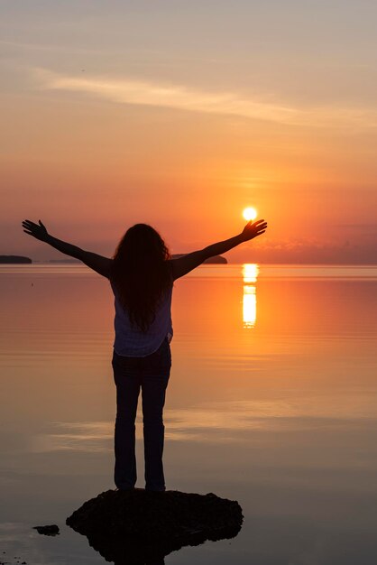 Foto een vrouw met haar armen uitgestrekt voor een zonsondergang