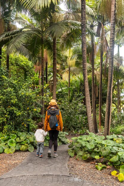 Een vrouw met haar zoon die in een botanische tuin loopt met haar familie.