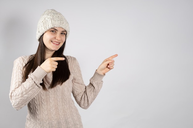 Een vrouw met hoed en trui wijst met haar vingers naar een plek voor tekst