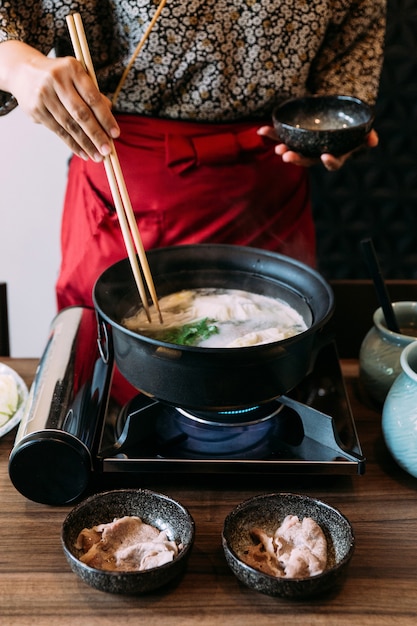 Een vrouw met kimono-kokende sukiyaki-groenten.