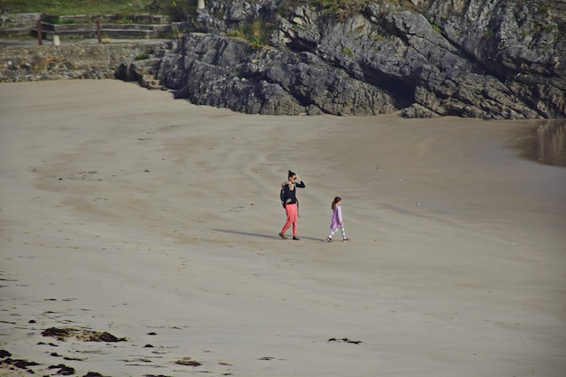 Een vrouw met kinderen loopt langs het strand naar het water the way of st james northern route spain