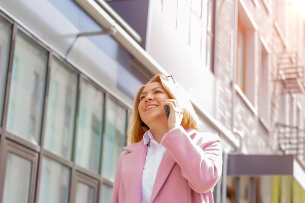 Een vrouw met kort bruin haar loopt door de stad en praat in de lente aan de telefoon