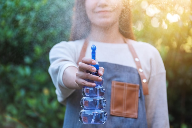 Een vrouw met schort die plant water geeft bij mistige spray in de tuin