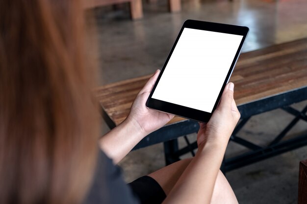 Een vrouw met zwarte tablet-pc met een wit leeg bureaublad in café