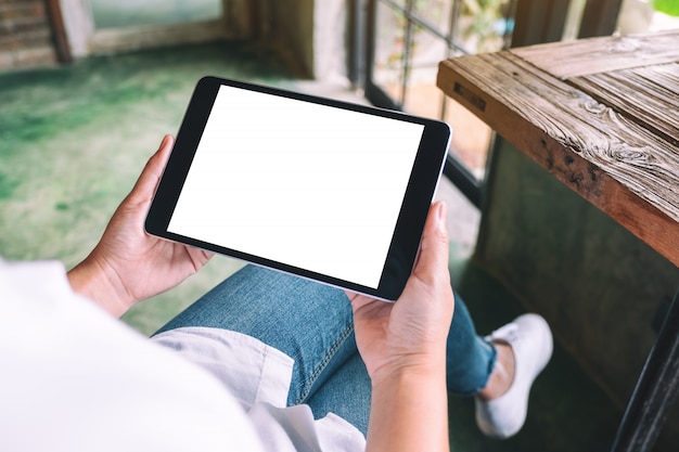 een vrouw met zwarte tablet-pc met lege witte desktop scherm zittend in café