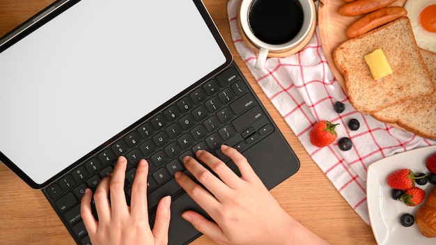 Een vrouw of student die op haar draagbare tabletcomputer op het toetsenbord aan het typen is