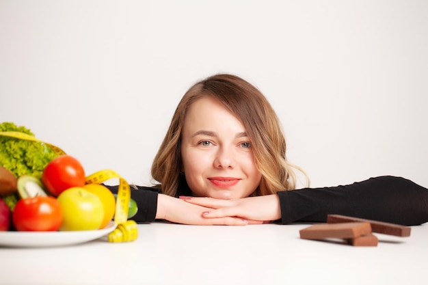 Een vrouw op dieet maakt een keuze tussen gezond eten en ongezond eten.