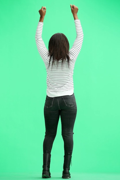 Een vrouw op een groene achtergrond in volle hoogte stak haar handen omhoog