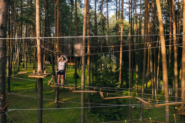 Een vrouw overwint een obstakel in een touwstadje een vrouw in een touwpark in het bos