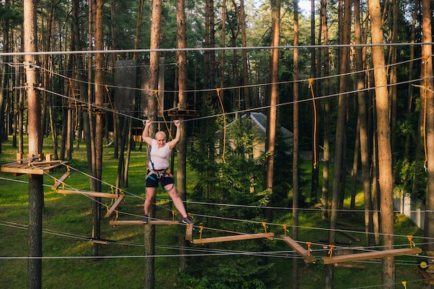 Een vrouw overwint een obstakel in een touwstadje Een vrouw in een touwpark in het bos