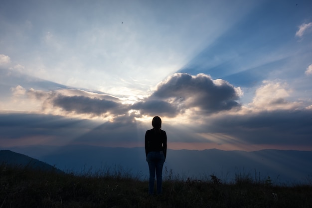 Een vrouw permanent en kijken naar zonsondergang met uitzicht op de bergen in de avond