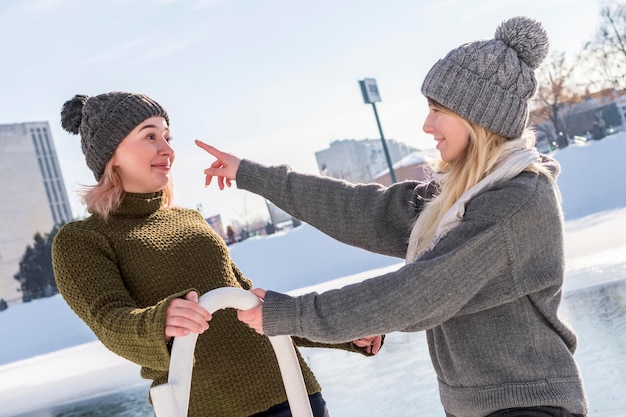 een vrouw probeert de neus van haar vriend aan te raken terwijl ze in de winter bij de rivier staat