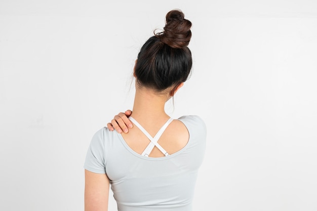 Een vrouw raakt haar pijnlijke nek aan tegen een witte achtergrond