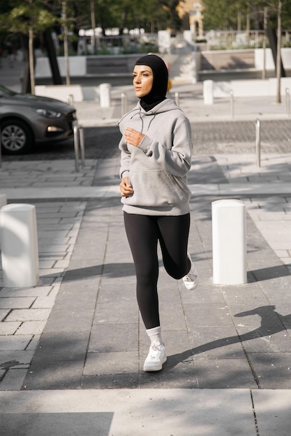 Een vrouw rent door de straat met een grijze hoodie aan met het woord 'i' erop.