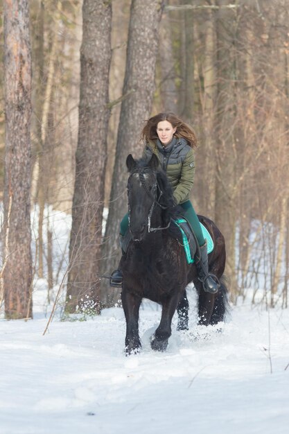 Een vrouw rijdt op een donkerbruin paard in het bos