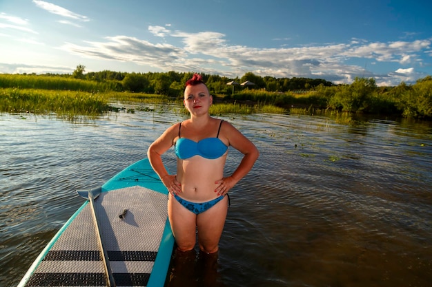 Een vrouw staat bij het sapboard aan de kust en bereidt zich voor om te zwemmen