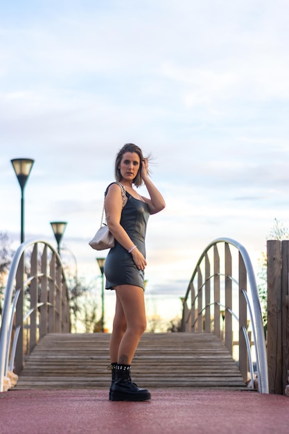 Een vrouw staat op een brug met haar hand op haar hoofd