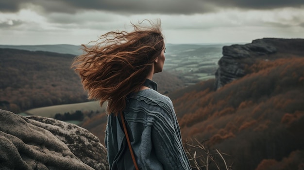 Een vrouw staat op een klif en kijkt naar het landschap en de lucht is bewolkt.