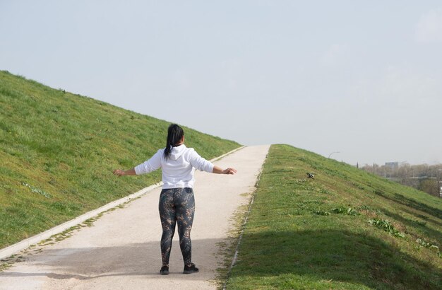 een vrouw staat op een pad met haar armen uitgestrekt