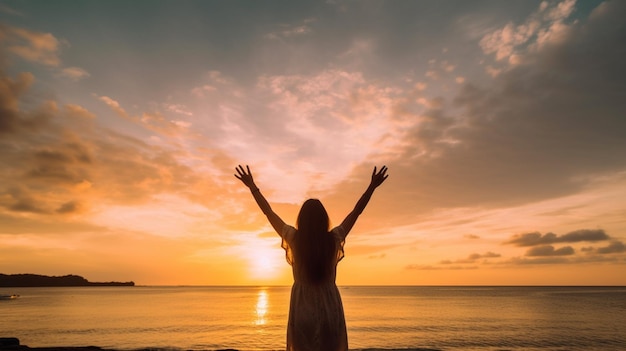 Een vrouw staat op het strand met haar armen omhoog met de zon achter haar ondergaan.
