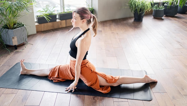 Een vrouw traint in een fitnessstudio op de mat asana pose doet yoga in sportkleding