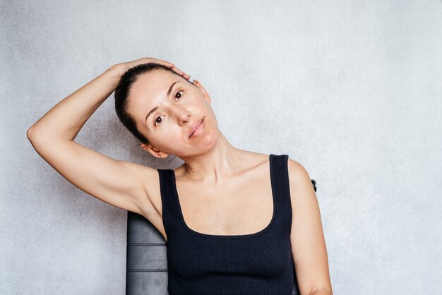 Een vrouw trekt zachtjes aan haar hoofd terwijl ze de mckenzie-methode doet om pijn in de nek te verlichten...