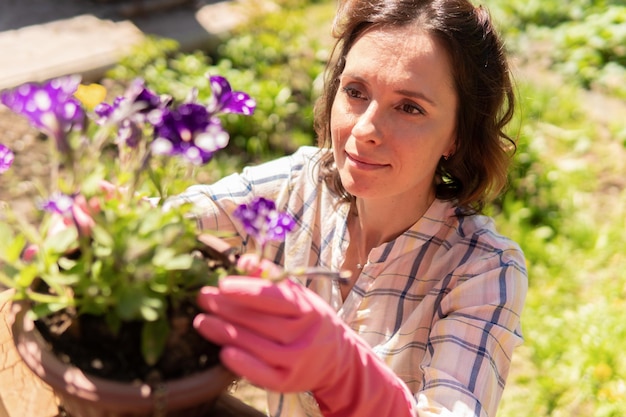 Een vrouw tuiniert in haar achtertuin, ze plant zaailingen.