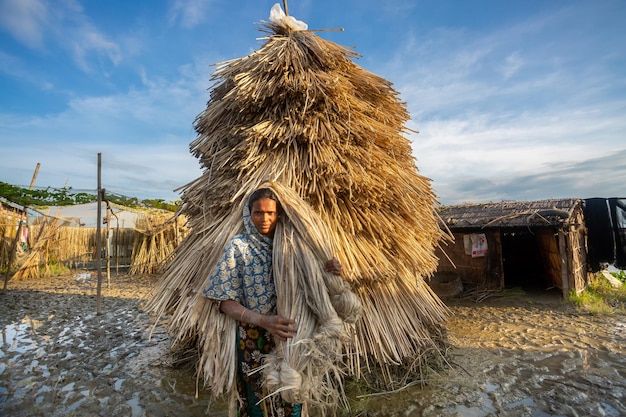 Een vrouw uit het dorp draagt natte jute op haar schouder in Bangladesh