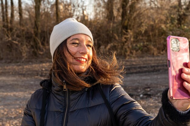 Foto een vrouw van middelbare leeftijd in winterkleding die een selfie maakt bij een rivier - concept van mensen in recreatie