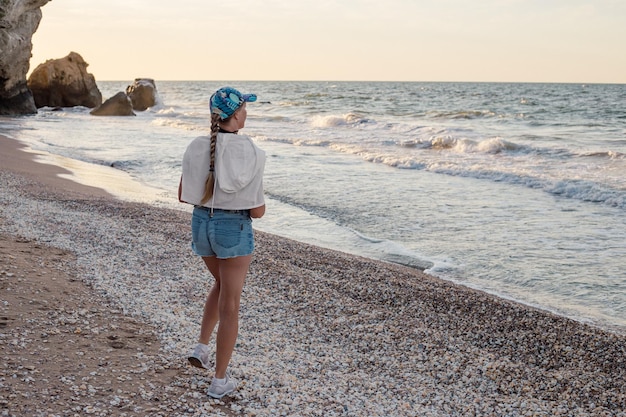 Een vrouw van middelbare leeftijd met een vlecht in een pet en korte broek op de kust reizen en toerisme