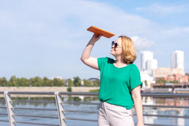 Een vrouw van middelbare leeftijd met een zonnebril die in de verte kijkt tegen de achtergrond van de stadsdijk