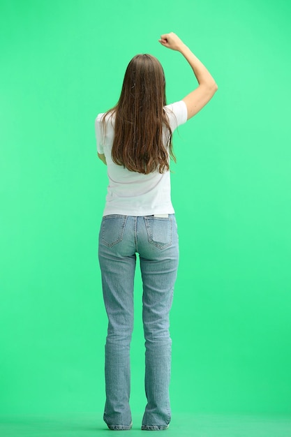 Een vrouw van volle lengte op een groene achtergrond verheugt zich