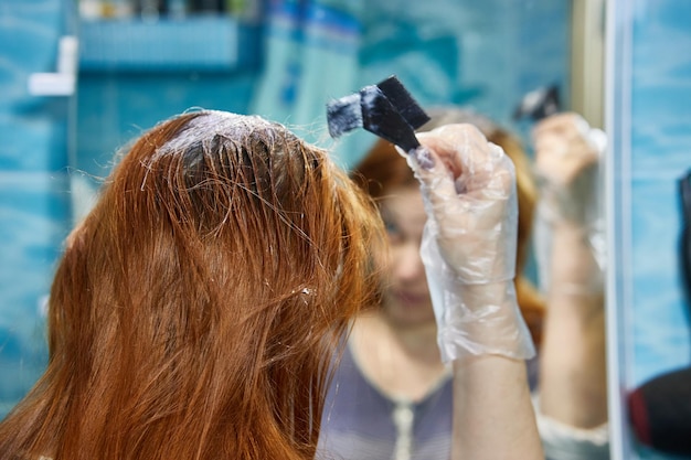 Een vrouw verft haar haar rood en kleurt de haarwortels met henna of verf